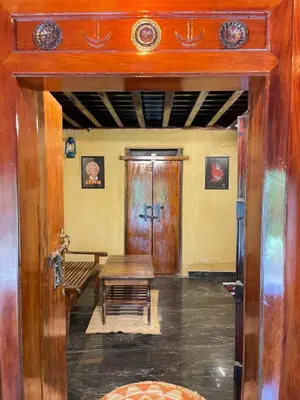 a room with a bench and a wooden door at Aravanazhi tharavadu in Thirunelli