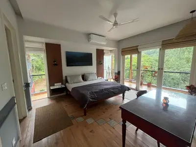 a bedroom with a bed and a table and windows at Luxury Villa in Wayanad Hills with Private Garden in Wayanad