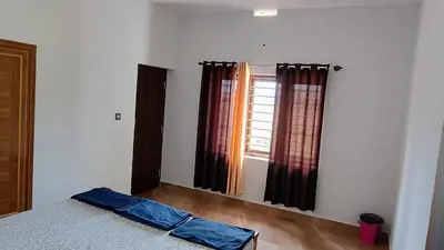 a bedroom with a bed and a window with curtains at Nagesh paikera biligeri in Madikeri