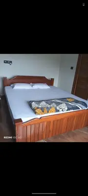 a bed with a wooden frame with a blanket on it at Nagesh paikera biligeri in Madikeri