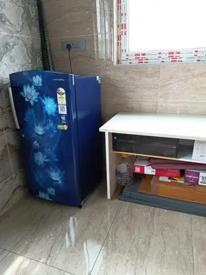 a blue refrigerator sitting next to a table at Yellow Bliss - 1BK Apartment in Coimbatore