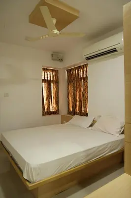 a bedroom with a large bed with a ceiling fan at Aaru Residency in Coimbatore