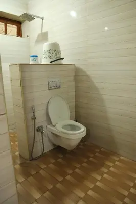 a bathroom with a toilet in a wooden floor at Aaru Residency in Coimbatore