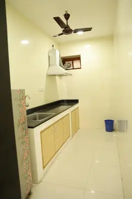 a kitchen with a sink and a ceiling fan at Aaru Residency in Coimbatore
