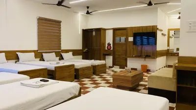 a room with beds and a tv and a checkered floor at Hotel National Tourist Home in Trichūr