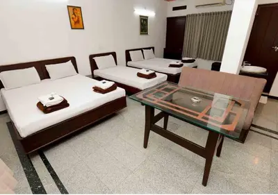 a room with two beds and a glass table at Hotel National Tourist Home in Trichūr