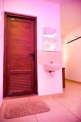 a bathroom with a sink and a wooden door at Stay Point Premium Capsule and Rooms in Calicut Beach in Kozhikode