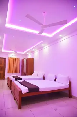 two beds in a room with a ceiling fan at Stay Point Premium Capsule and Rooms in Calicut Beach in Kozhikode
