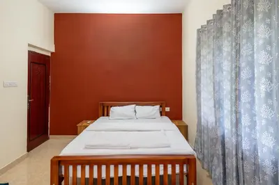 a bedroom with a bed and a curtain at CLUB 4 Homestay in Nedumbassery