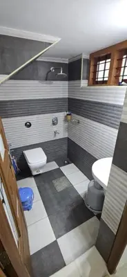 a bathroom with a black and white checkered floor at Leela cottage in Kozhikode