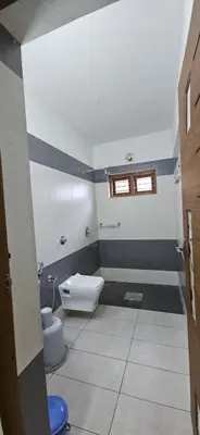 a bathroom with a toilet and a window in it at Leela cottage in Kozhikode