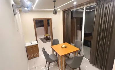 a dining room with a wooden table and chairs at Vilstay Premium- Fathima 2BHK in Kottakkal