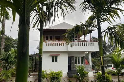 a white house with palm trees in front of it at S R Retreat in Dodbelvangala