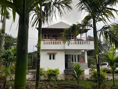 a white house with palm trees in front of it at S R Retreat in Dodbelvangala