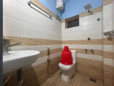 a bathroom with a sink and a toilet with a red container at Anugraha inn in Guruvāyūr