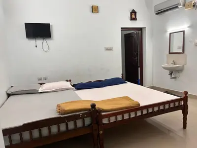 a bedroom with a bed with a sink and a tv on the wall at Anugraha inn in Guruvāyūr