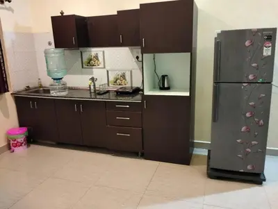 a kitchen with brown cabinets and a refrigerator at Daffodil serviced apartments in Mysore