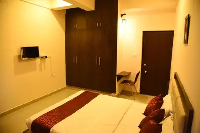a bedroom with a bed and a cabinet and a desk at Daffodil serviced apartments in Mysore