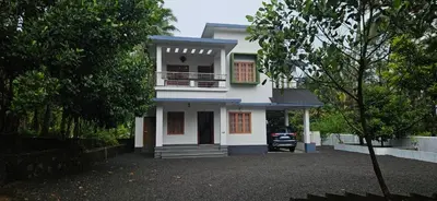 a white house with a balcony and a driveway at A cozy home bythe waterstream, tourist places near waynad in Kodenchery