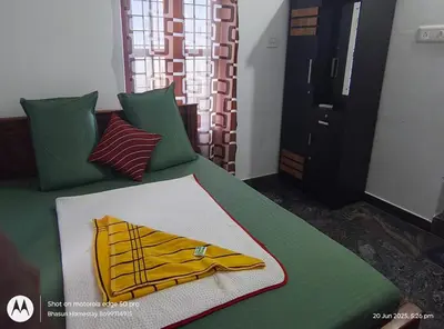 a green bed with a yellow robe on it at Bhasuri AC Villa with Kitchen 1 in Agali