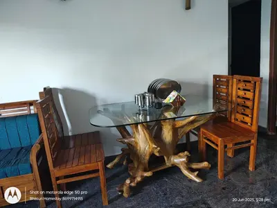 a glass table with a tree stump base and two chairs at Bhasuri AC Villa with Kitchen 1 in Agali