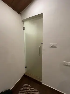 a bathroom with a glass door in a room at Naad Alaya Estate Stay in Siddapur