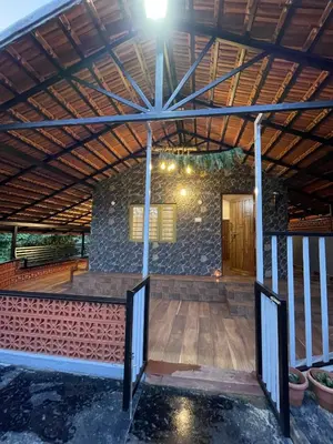 a patio with a wooden floor and a stone wall at Naad Alaya Estate Stay in Siddapur