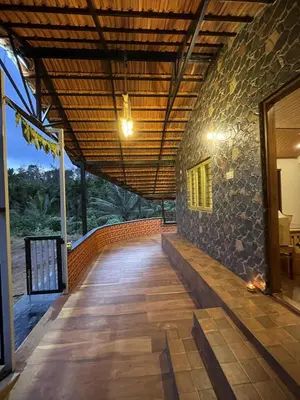 a hallway of a house with a stone wall at Naad Alaya Estate Stay in Siddapur