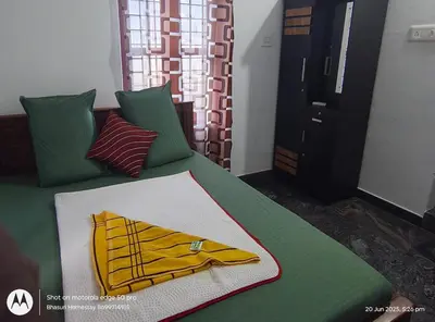 a green bed with a yellow robe on it at Bhasuri NON-AC Villa with Kitchen in Agali