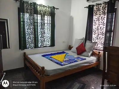 a bed in a room with two windows at Bhasuri NON-AC Villa with Kitchen in Agali