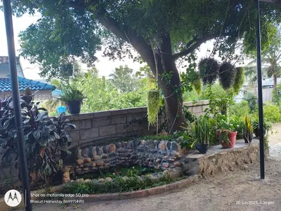 a garden with a retaining wall and a tree at Bhasuri NON-AC Villa with Kitchen in Agali