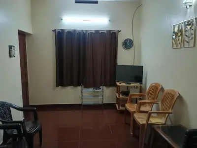 a room with a television and chairs and a curtain at Home away from home in Palakkad in Palakkad