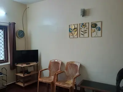 a living room with two chairs and a television at Home away from home in Palakkad in Palakkad