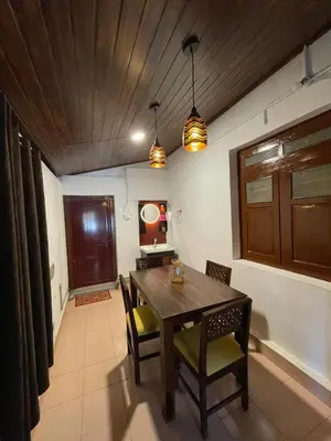 a dining room with a wooden table and chairs at Emnic Cottage Homestay in Meppādi