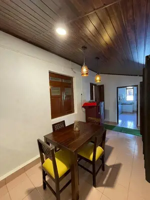a dining room with a wooden table and yellow chairs at Emnic Cottage Homestay in Meppādi