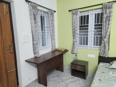 a bedroom with a desk and two windows at VPM Homestay in Coimbatore
