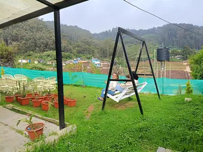 a child sitting on a swing in a garden at Meadows Mountain Villa in Ooty