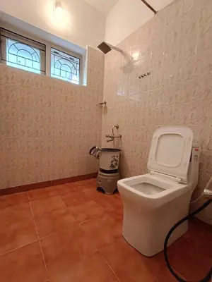 a bathroom with a white toilet and a window at Meadows Mountain Villa in Ooty