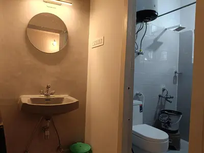 a bathroom with a sink and a toilet and a mirror at Meadows Mountain Villa in Ooty