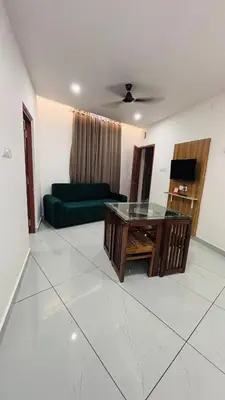 a living room with a green couch and a table at LF Apartment in Kozhikode