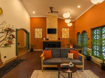 a living room with orange walls and a couch at The Hosteller Bam Coorg in Madikeri