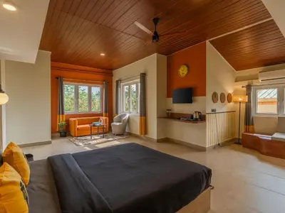 a bedroom with a bed and a living room at The Hosteller Bam Coorg in Madikeri