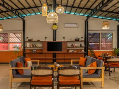 a living room with a table and chairs and a tv at The Hosteller Bam Coorg in Madikeri