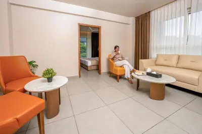 a woman sitting on a couch in a living room at MYSA Sky Suites, Lakkidi in Vythiri
