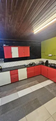 a room with a bed and red and green cabinets at Romanzia Village Homestay in Mānantoddy