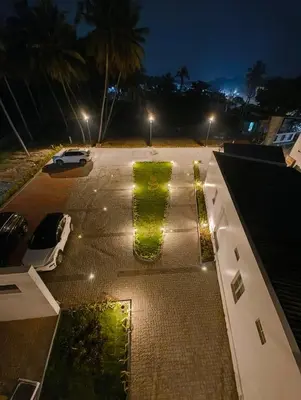 a parking lot at night with a green hedge at Arthana Residency Hotel