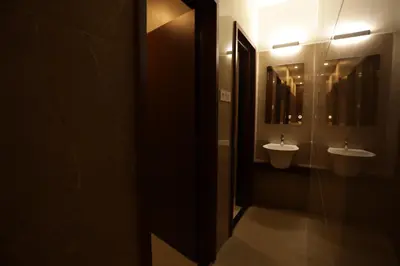 a bathroom with two sinks and two mirrors at Arthana Residency Hotel