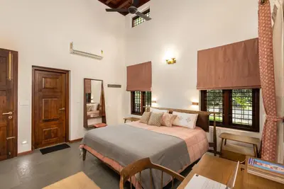 a bedroom with a bed and a table and chairs at Eka in Kodungallūr