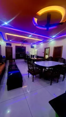 a room with tables and chairs and purple lights at NesaraVana - Ecostay in Hārohalli
