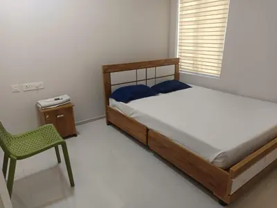 a bedroom with a bed and a chair and a window at Divin Kalpaka 150 meter to temple in Guruvāyūr